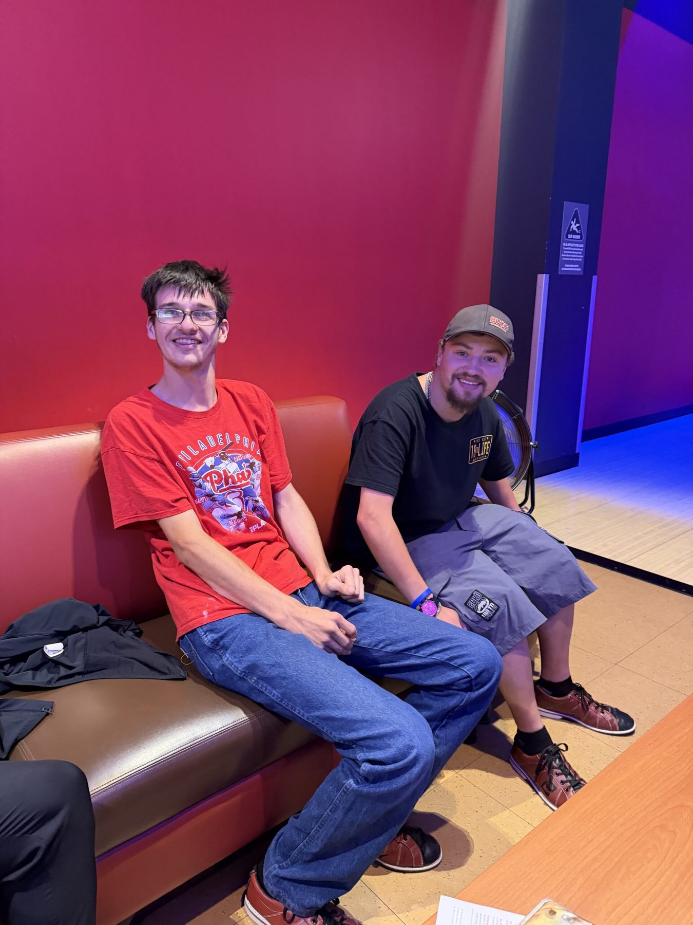 Two friends smiling together at a bowling alley